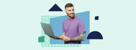 Young bearded man with tattoos holding a laptop